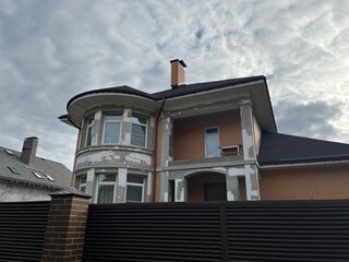 Residential building under construction with exposed brick and plaster, showcasing architectural details and a cloudy sky, representing home renovation and development process