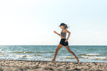 Marathon runner near coast, Female marathon trainee maintaining focused pace while running near beach with sunlight