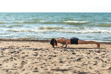 Individual performing plank on sandy beach, Person maintaining strict plank position amid tranquil seaside environment
