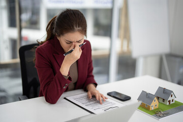 Asian adult real estate agent facing stress reviewing property contract in modern office...