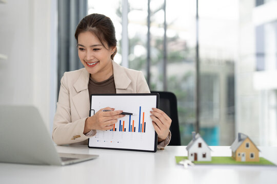 Asian adult real estate agent presenting property market data online in modern office for home sales investment strategy