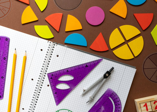 back to school concept. Wooden fraction pieces showing 1, 1/2, 1/6, 1/8, and 1/5 rest on orange background, yellow letter block, combining math and play