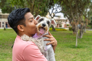 Young man showing affection kissing his pet dog