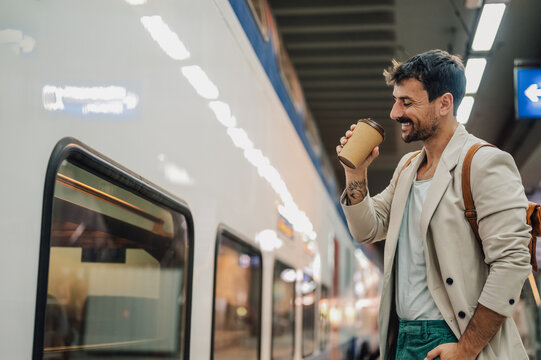 Happy man commuting by train enjoying coffee