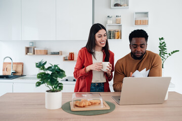 Diverse couple managing finances online in kitchen