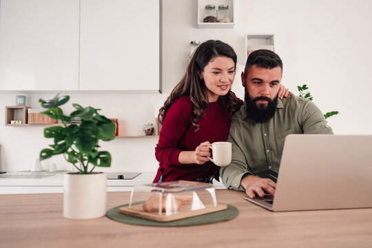 Couple planning online budget using laptop in kitchen