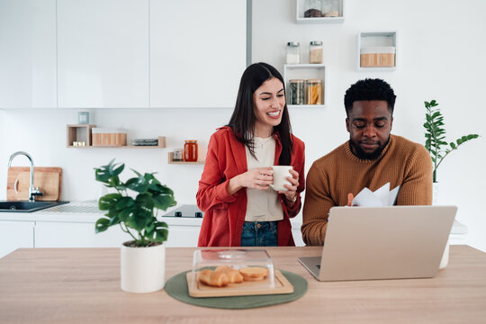 Diverse couple managing finances online in kitchen - Powered by Adobe