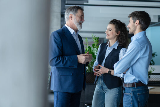 Three busy coworkers discussing project, standing in modern office