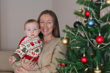 Portrait of mom and her newborn by the Christmas tree.