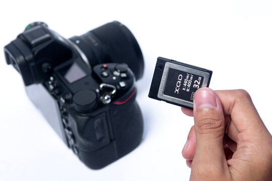 Karawang, West Java - October 27 2025 : hand holding XQD or mirrorless camera memory into the slot