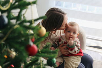 Mother with her baby by the Christmas tree.