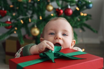 Cute little baby opening the Christmas present. Close up, background.
