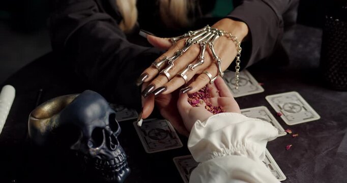 Witch reading client palm in mystical fortune ritual with tarot cards