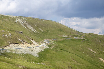 Scenic stretch of Romania&rsquo;s Transalpina road curving through dense forest and mountainous terrain. Ideal for editorial, travel, infrastructure, or nature photography themes.