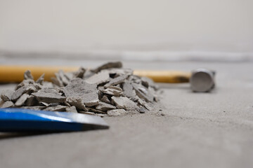 Close-up of chisel and hammer with pile of broken mortar on floor during renovation. Image with copyspace.