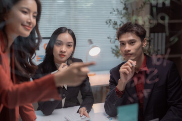 Young Asian business professionals collaborating and discussing new strategies and financial plans, working together during a corporate meeting in a modern office environment