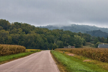 Early Autumn landscape of a road passing through rolling hills in Wisconsin’s Driftless Area near Trempealeau, Wisconsin.