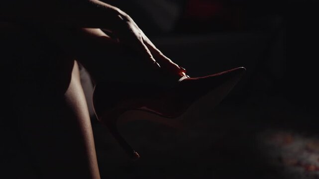Close up of seductive woman in nightclub, sharp lighting highlighting her leg, she runs her hand over her ankle, creating an alluring atmosphere