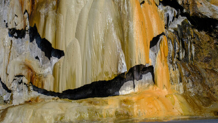 travertine waterfall close-up image, with mineral waters, the waterfall turned into chalky and colorful travertines.