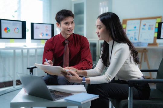 Asian business colleagues collaborating and analyzing data during an office meeting, brainstorming ideas, and sharing insights while planning future strategies with financial charts on screens