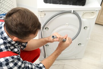 Professional repairman fixing broken washing machine indoors