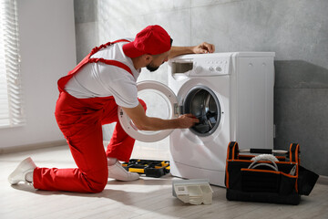 Professional repairman fixing broken washing machine indoors