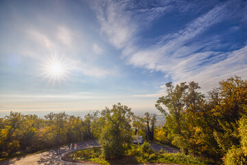 a landscape with a mountain road on a sunny autumn day with the sun shining