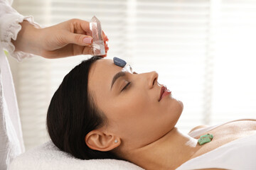 Woman undergoing crystal therapy to heal or restore her aura indoors, closeup