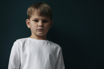 Upset little boy on black background, space for text
