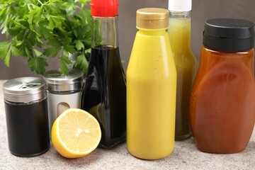 Bottles of different tasty sauces and products on grey table, closeup