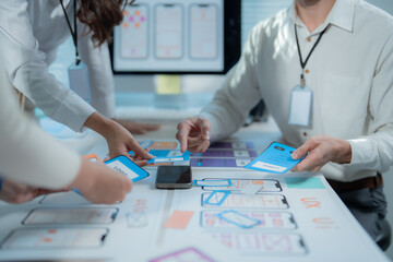 UX designers collaborating at an office table, discussing mobile app wireframes and user interface prototypes to plan the next phase of development