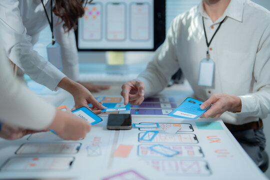 UX designers collaborating at an office table, discussing mobile app wireframes and user interface prototypes to plan the next phase of development