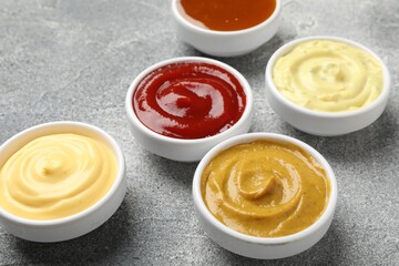 Different tasty sauces in bowls on grey table, closeup