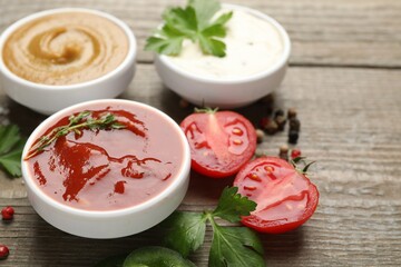 Different sauces, spices and parsley on wooden table, closeup