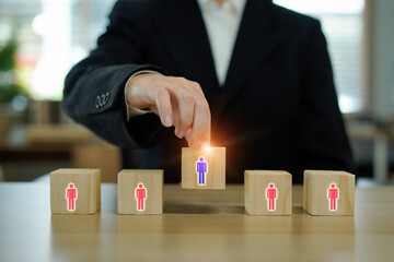 Wooden blocks with business person icons are being by hand symbolizing leadership and teamwork in...