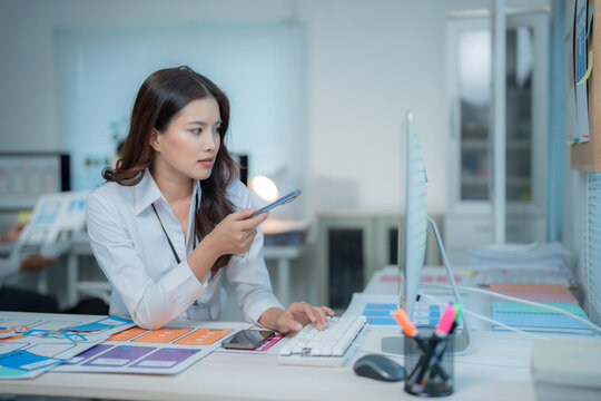 Woman UI UX designer concentrating on developing mobile application interfaces on a computer in a modern office, analyzing design elements and planning digital solutions
