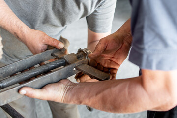 Plano acercamiento de manos trabajando en reparación de pieza de hierro en maquinaria agrícola