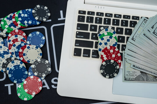 Online casino concept with poker chips, laptop and stacks of US dollars symbolizing betting and fortune