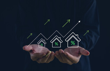 Real estate investment growth concept with businessman hands holding rising house icons and interest rate symbols. Digital finance, housing market increase, and property value strategy for investors.
