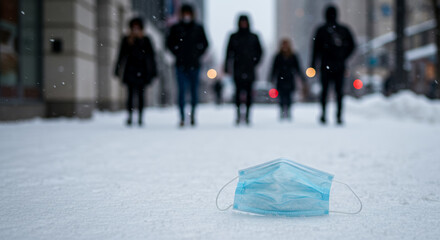 Discarded blue face mask lying on snow-covered street in winter  