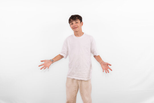 handsome young happy positive casual dressed smiling white male model teenager open hands out as welcome or presenting Voil&agrave;, ta-da here it is,  plain background studio setting.