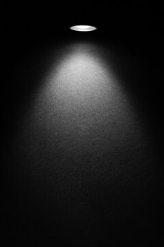 Single spotlight on a dark textured wall with a cone beam and soft vignette. Minimal versatile background with room for headline or logo.