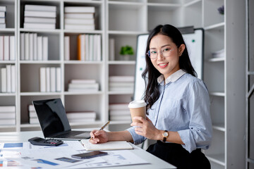 Accounting business concept, Accountant woman drinking coffee and writing information in notebook while