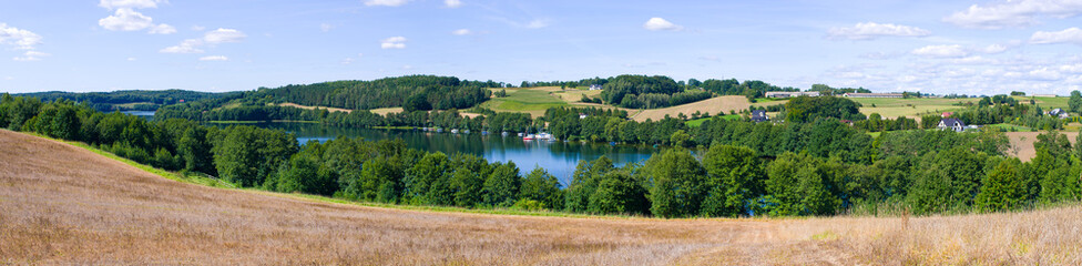 Idyllic lakeside landscape with rolling hills and summer sky, Kaszuby, Poland