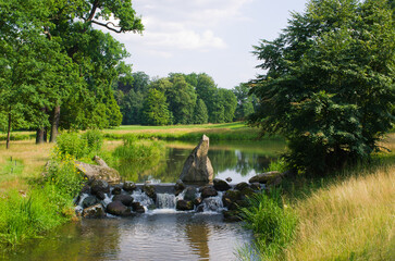 Serene park lake reflects lush green trees and blue sky