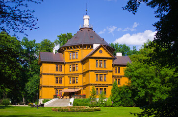 Stunning historic yellow mansion surrounded by lush green trees, Antonin, Poland