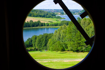 Vibrant lakeside vista framed by dark circular window, Kaszuby, Poland