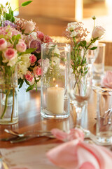 A stunning table is adorned with vibrant flowers and flickering candles, creating a romantic atmosphere for a gathering. The soft afternoon light enhances the setting, making it inviting.
