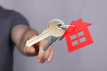 A hand holding a key with a house-shaped keychain, representing home ownership, new beginnings, real estate, mortgage. Perfect for property mark