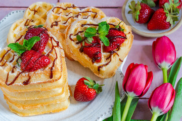 Heart-shaped belgian waffles decorated with fresh strawberries